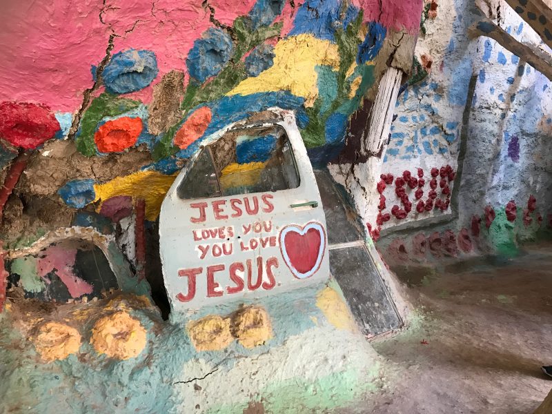 A car door that says Jesus Loves You inside Salvation Mountain